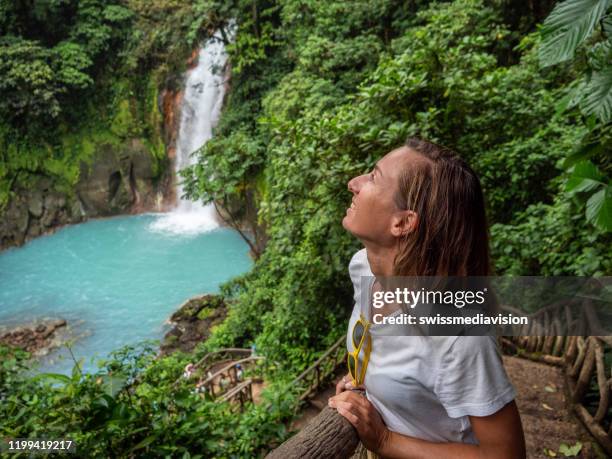 young woman contemplating turquoise waterfall in costa rica - costa rica waterfall stock pictures, royalty-free photos & images