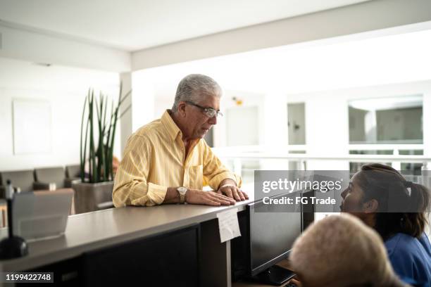 senior patient at hospital reception / secretary - entering hospital stock pictures, royalty-free photos & images