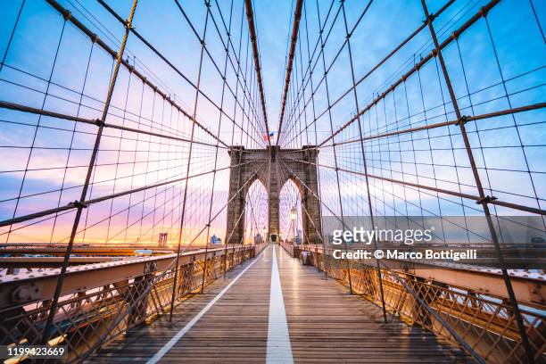 brooklyin bridge's pedestrian walkway at sunrise, new york city - brooklyn new york stockfoto's en -beelden