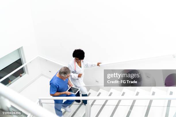 vrouwelijke arts en mannelijke verpleegster die omhoog op trap bij het ziekenhuis bewegen - hospital connectivity stockfoto's en -beelden