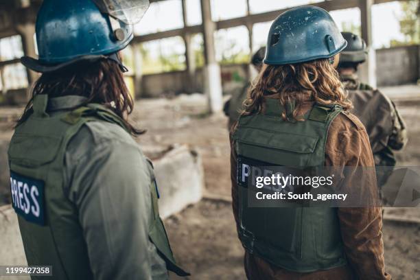 journalisten im kriegsgebiet mit soldaten - fernsehreporter stock-fotos und bilder