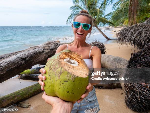 トロピカルビーチでココナッツを共有するカップル - 2 coconut drinks ストックフォトと画像