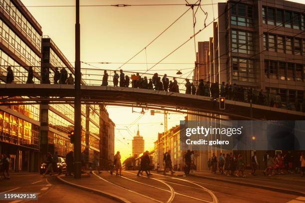 mensen lopen over brug in münchen tijdens zonsondergang uur - munich stockfoto's en -beelden