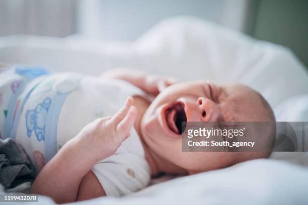 baby junge liegt allein auf dem bett und weint - schreiendes baby stock-fotos und bilder