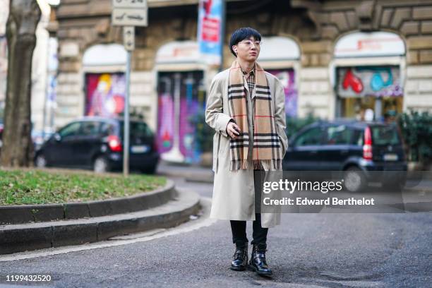 Guest wears a trench coat, a brown checked scarf, black pants, black Vuitton shoes, glasses, outside Reshake, during Milan Fashion Week Menswear...