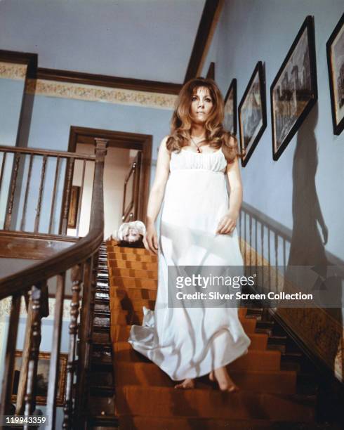 Ingrid Pitt , Polish actress, wearing a long white dress, walking down a staircase in a publicity still issued for the film, 'The Vampire Lovers',...