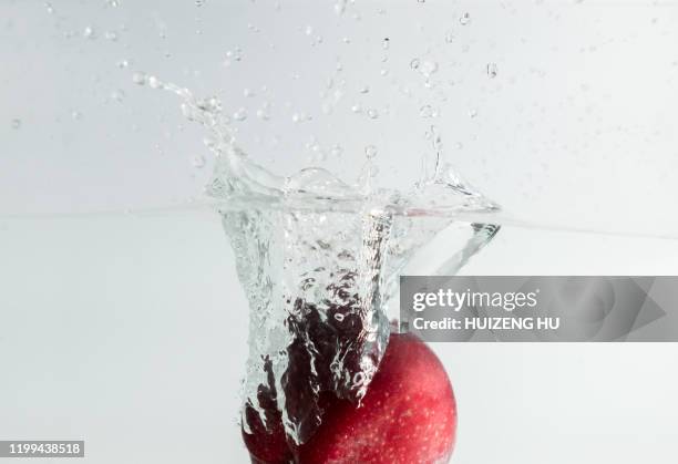 closeup of red apple splash in water - apple water splashing stock pictures, royalty-free photos & images