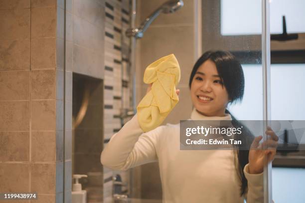 eine asiatische chinesische teenager-mädchen reinigung ihr badezimmer wischen es mit einem gelben kleid - mikrofaser stock-fotos und bilder