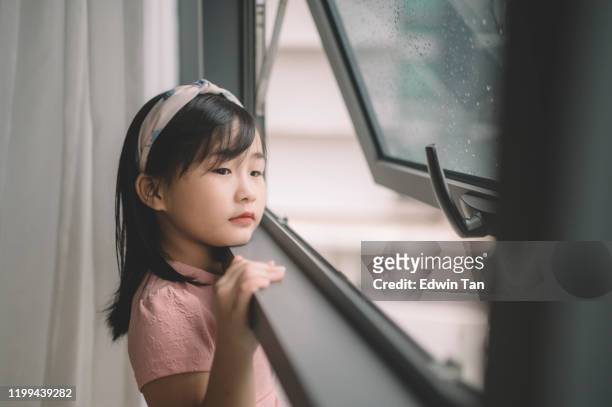 彼女の寝室の窓から外を見ているアジアの中国の幼い子供 - very young asian girls ストックフォトと画像