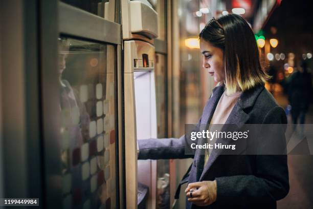 giovane donna che usa bancomat - sportello bancomat foto e immagini stock