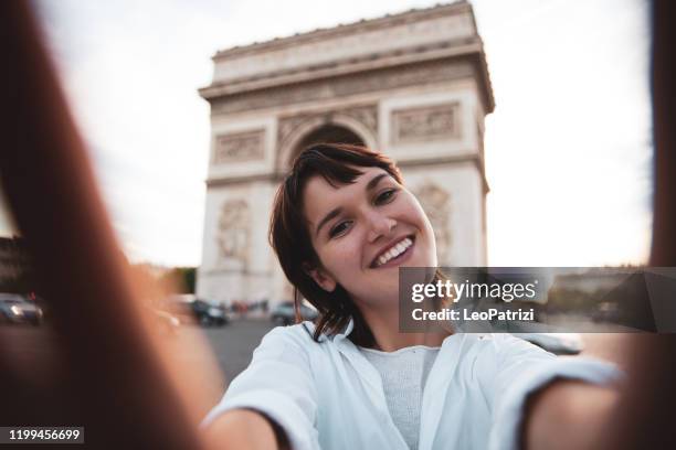 young caucasian women walking in paris in the city center talking and texting on the phone and commuting, exploring city landmarks, tour eiffel and arc de triomphe. - sassy paris stock pictures, royalty-free photos & images