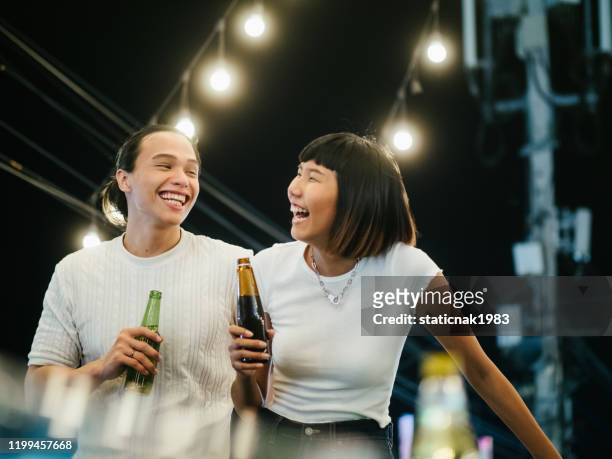 jeunes couples asiatiques griller avec la bière à la partie de toit - asian drink photos et images de collection