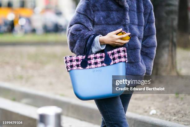 Guest wears a purple fluffy puffer jacket, a blue "O Bag" with a checked tweed part, outside Reshake, during Milan Fashion Week Menswear Fall/Winter...