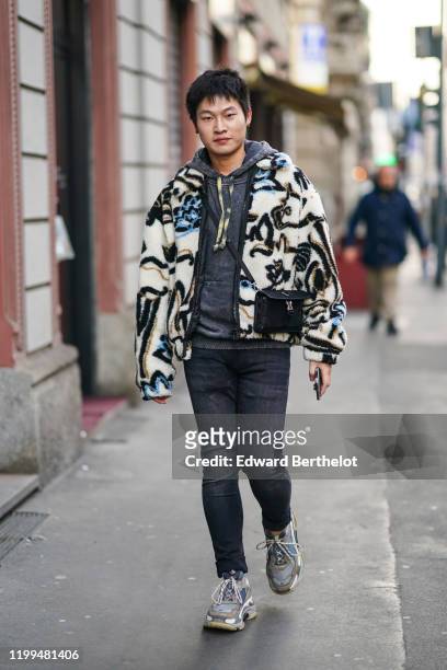 Guest wears a gray hoodie sweater, a black bag, a fluffy winter jacket with geometric printed patterns, black denim jeans, Balenciaga sneakers,...