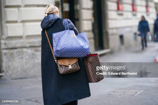 Guest wears a winter puffer long coat with a fluffy part, a blue Goyard bag, a Vuitton monogram bag and a Vuitton large checked bag, outside Reshake,...
