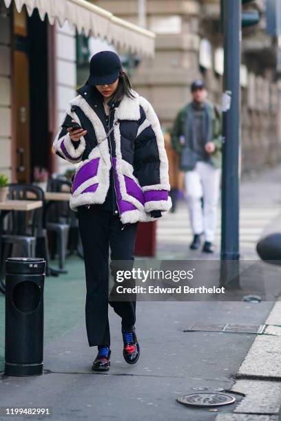 Guest wears a black cap, a black white and purple puffer jacket with fluffy parts, black flared pants, black leather shoes with blue shoelace and...