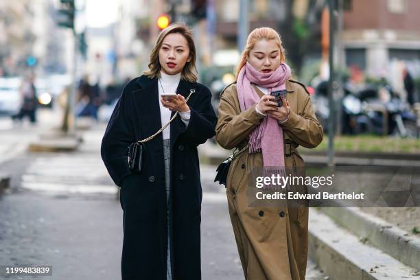 Guest wears a white turtleneck pullover, a necklace, a shoulder strapped bag, a black long coat ; a guest wears a pink scarf, a brown trench coat,...