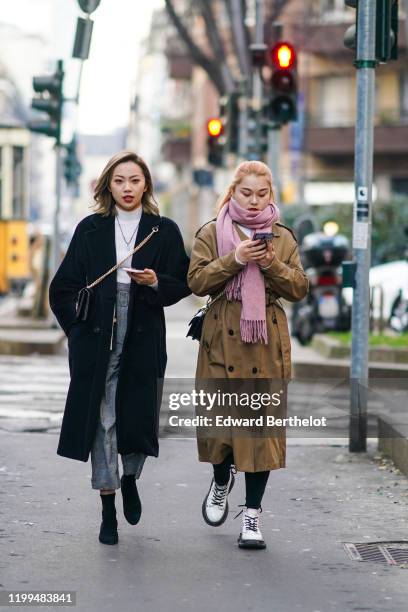 Guest wears a white turtleneck pullover, a necklace, a shoulder strapped bag, a black long coat, gray cropped pants, black shoes ; a guest wears a...