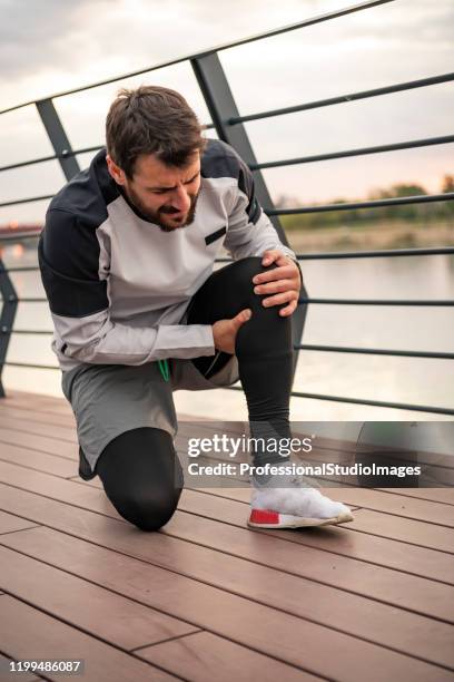 handsome young sportsman have physical injury of knee during a practice - muscle cramps stock pictures, royalty-free photos & images