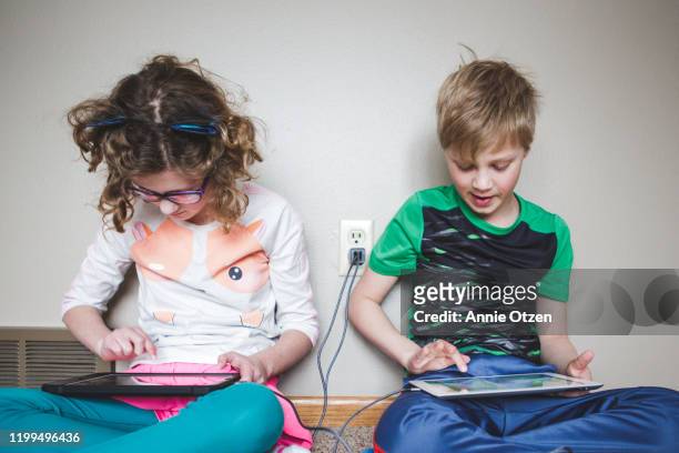 Kids sitting side by side working on tablets