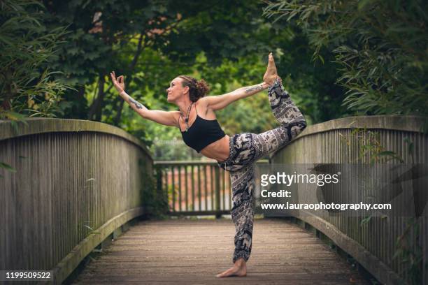 woman outdoors practicing yoga on bridge - milton keynes stockfoto's en -beelden