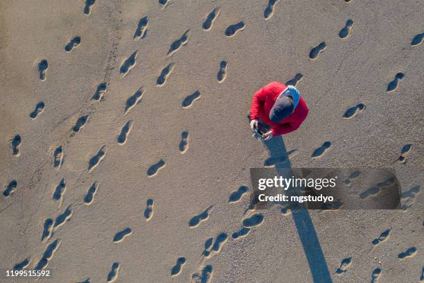 luchtfoto van man die een drone op tropisch strand bestuurt - voetafdruk stockfoto's en -beelden