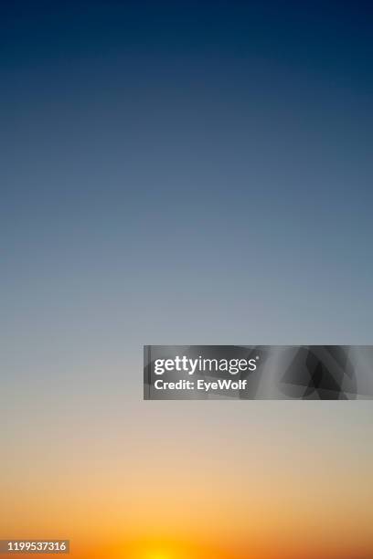 sunset sky color gradient from orange to dark blue - wolf wallpaper stock-fotos und bilder