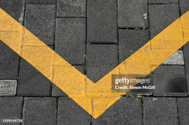 yellow painted v-shaped line on grey paving stones - letter v stock pictures, royalty-free photos & images