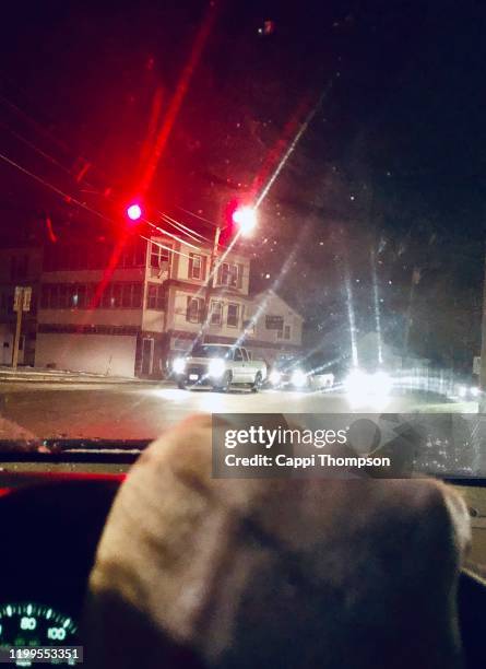 driver with hand on steering wheel stopped at red traffic light - 赤信号地区 ストックフォトと画像