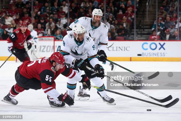 Jason Demers of the Arizona Coyotes attempts to clear the puck from Evander Kane and Joe Thornton of the San Jose Sharks during the second period of...