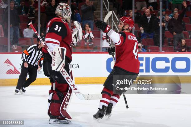 Goaltender Adin Hill of the Arizona Coyotes celebrates with Niklas Hjalmarsson after defeating the San Jose Sharks in the NHL game at Gila River...