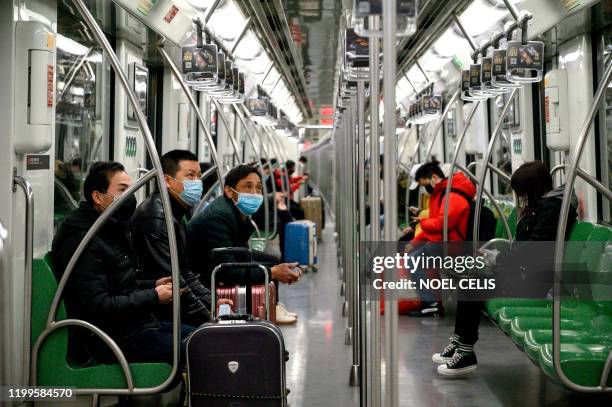 Passengers wearing protective face masks travel on a subway train in Shanghai on February 9, 2020. - The death toll from the novel coronavirus surged...