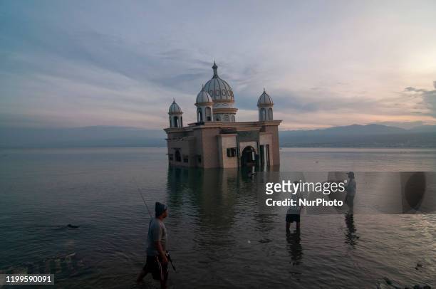 Several men fished near the floating mosque that collapsed into the sea on the coast of Kampung Lere, Palu, Central Sulawesi, Indonesia on February...