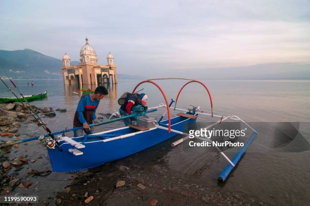 Fishermen prepare their boats and fishing rods to go to sea near the floating mosque that collapsed into the sea at Kampung Lere Beach, Palu, Central...