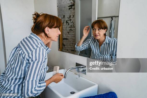 senior vrouw haar aanpassen in de badkamer - kammen stockfoto's en -beelden