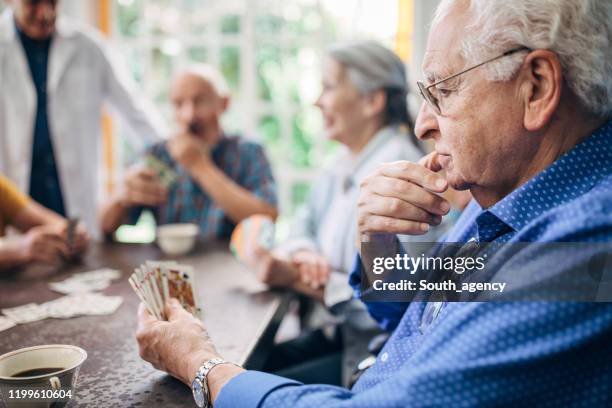 senior gentleman playing cards with friends - senior men playing cards stock pictures, royalty-free photos & images