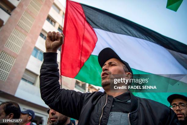 Moroccan man chants slogans next to a Palestinian flag during a demonstration against the US Middle East peace plan in the capital Rabat on February...