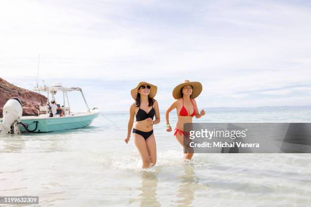 two young women coming out of ocean water - océano pacífico fotografías e imágenes de stock