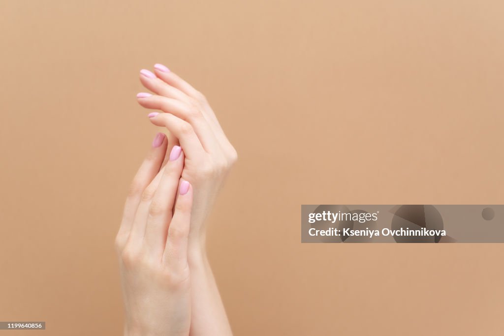 Tender hands with perfect blue and pink manicure on trendy pastel pink background. Place for text.