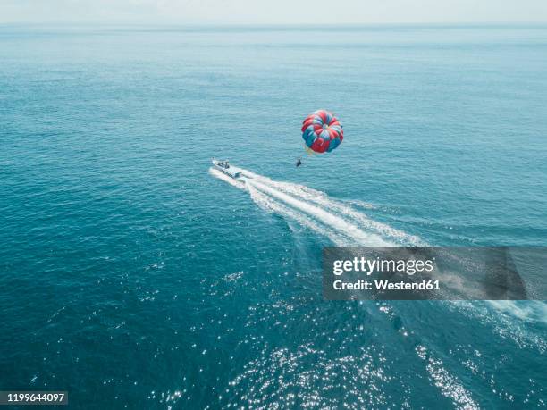 nusa dua, bali, nusa dua, aerial view of person parasailing and motorboat - parasailing imagens e fotografias de stock