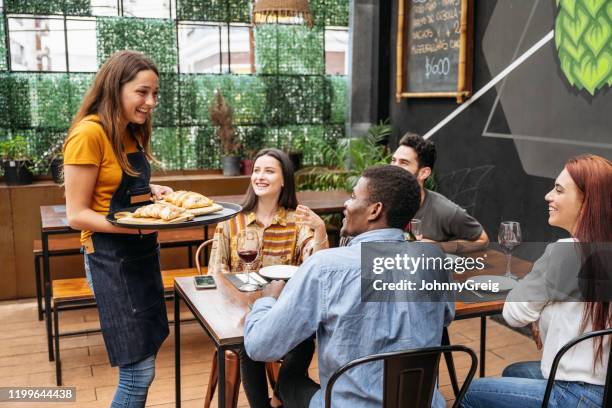 young waitress delivering empanadas to smiling customers - empanadas argentina stock pictures, royalty-free photos & images
