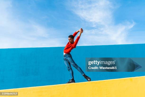 young man dancing on yellow wall - modeshow stock-fotos und bilder