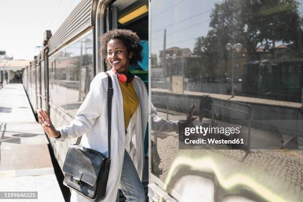 smiling young woman entering a train - train station stock-fotos und bilder