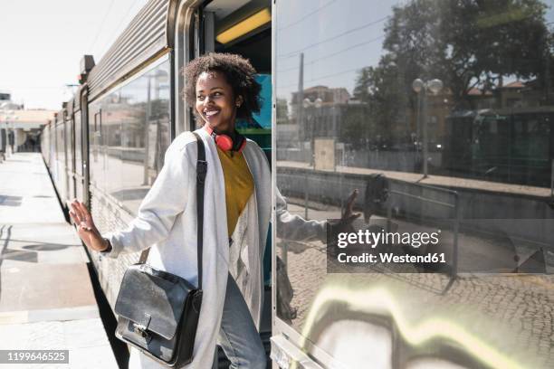 smiling young woman entering a train - train leaving stock pictures, royalty-free photos & images