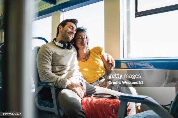 young couple with closed eyes relaxing in a train - bahnreisender stock-fotos und bilder