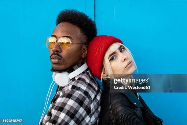 portrait of young couple back to back against blue background - 背對背 個照片及圖片檔