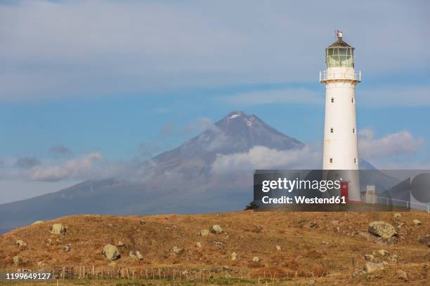 new zealand, south taranaki district, pungarehu, cape egmont lighthouse with mount taranaki volcano in background - cape egmont lighthouse stock pictures, royalty-free photos & images