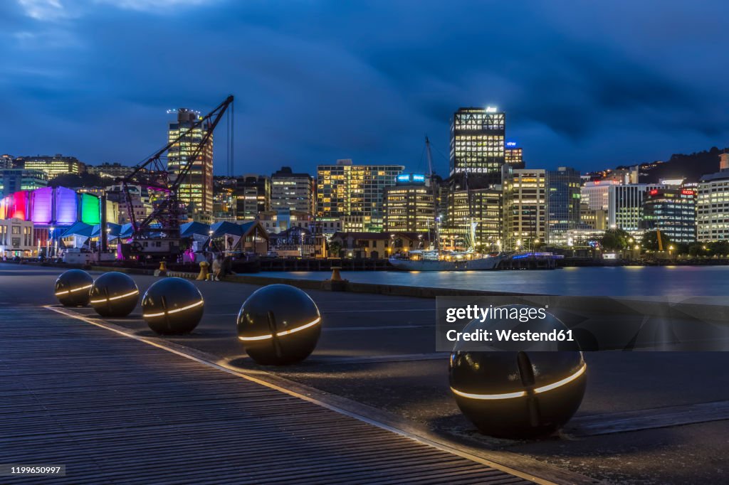New Zealand, Wellington, Light spheres along harbor at night with illuminated city skyline in background