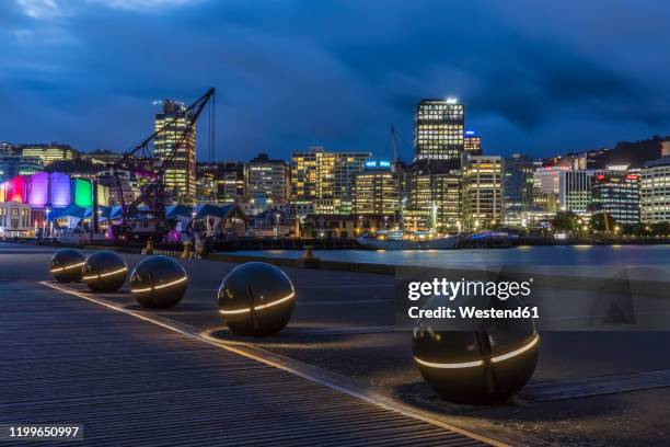 new zealand, wellington, light spheres along harbor at night with illuminated city skyline in background - wellington new zealand harbour stock pictures, royalty-free photos & images