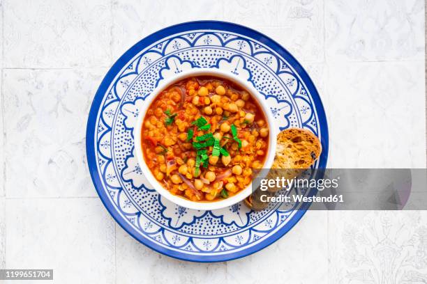 lentil and chickpea soup (red lentils, chickpeas, tomatoes, red onions, mint) - blue bowl stock-fotos und bilder